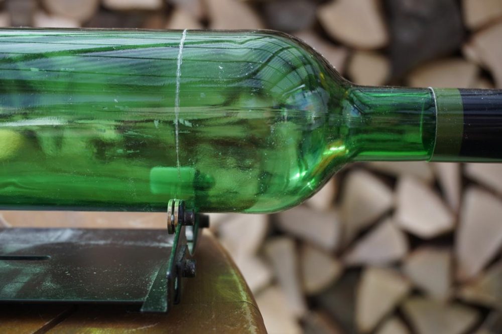Bild einer Weinflasche, die mit einem Glasflaschenschneider bearbeitet wird.

